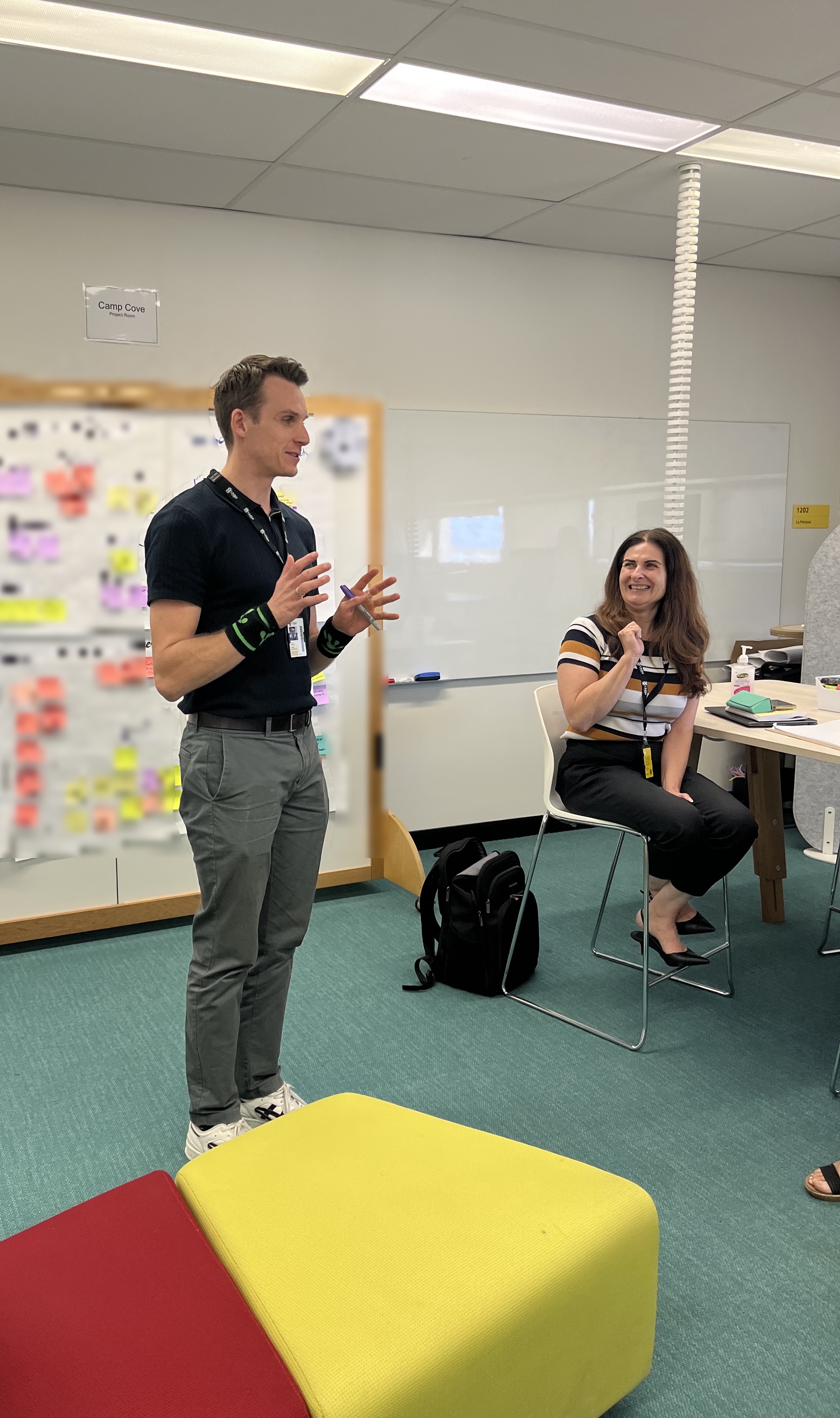 Xander facilitating a workshop beside a wall of mapped sticky notes